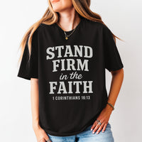Person wearing a black t-shirt with 'Stand Firm in the Faith' text on a plain background