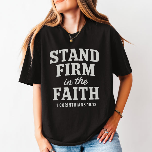 Person wearing a black t-shirt with 'Stand Firm in the Faith' text on a plain background