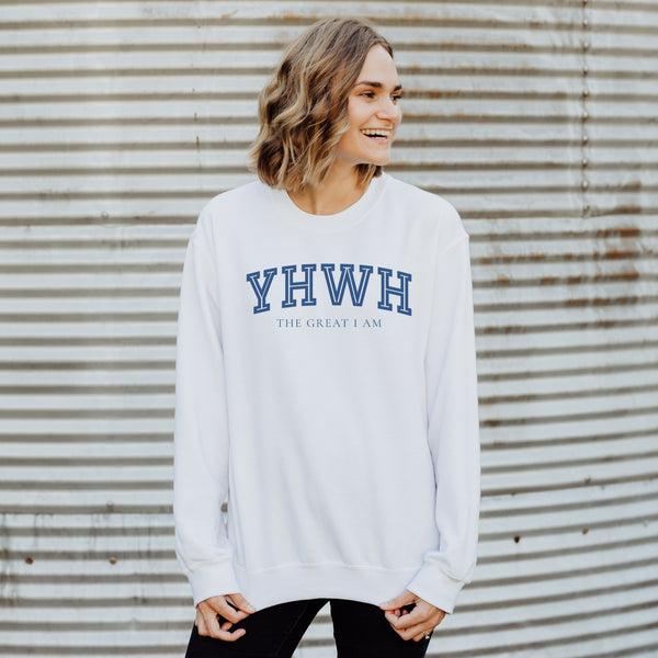 Person wearing a white sweatshirt with 'YHWH THE GREAT I AM' text against a corrugated metal background
