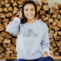 Woman wearing a gray sweatshirt with text and a graphic, sitting in front of stacked wood.