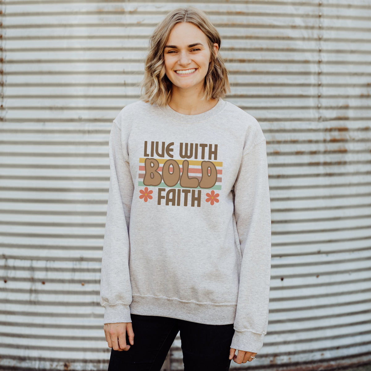Person wearing a gray sweatshirt with 'Live with Bold Faith' text against a corrugated metal background
