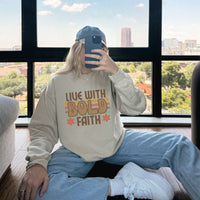 Person wearing a beige sweatshirt with 'Live with Bold Faith' text, sitting by a window with a cityscape view.