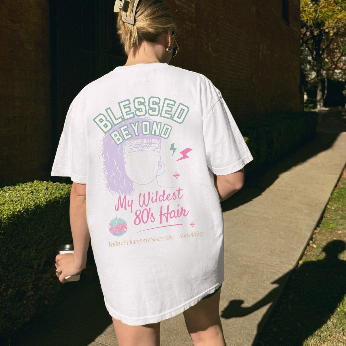 Person wearing a white t-shirt with text and graphics, walking outdoors.