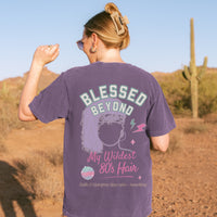 Person wearing a purple t-shirt with 'Blessed Beyond My Wildest 80's Hair' design in a desert setting