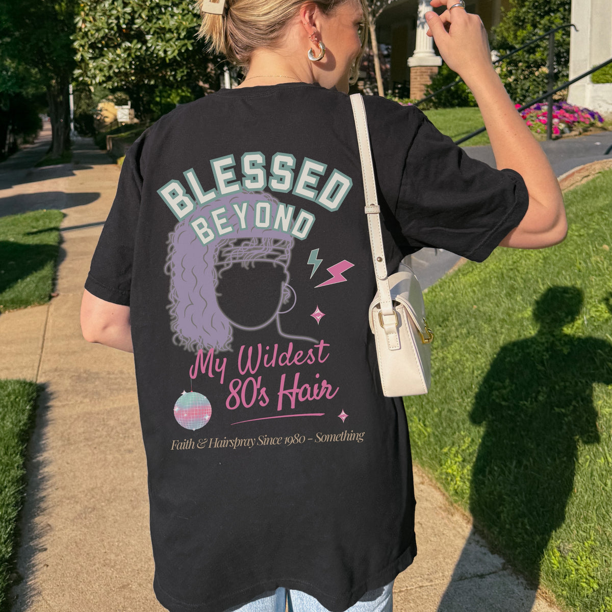 Person wearing a black t-shirt with a graphic design and text, standing outdoors.
