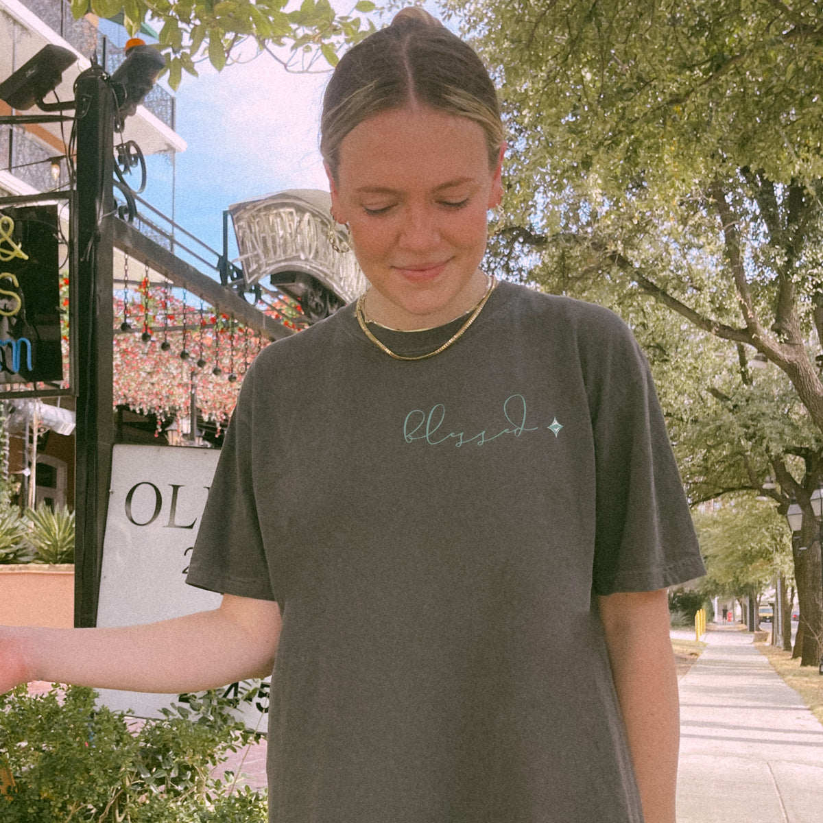 Person wearing a pepper t-shirt with 'blessed' text on a street background