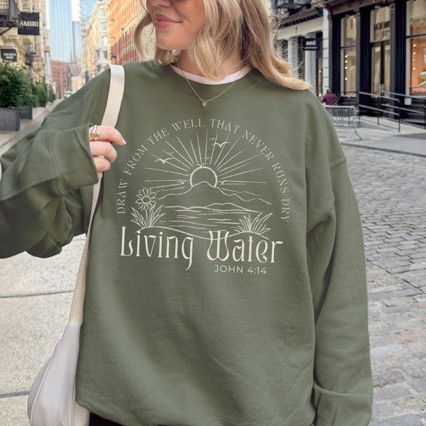 Person wearing a green sweatshirt with a printed design and text, standing on a city street.