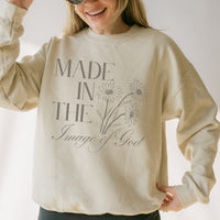 Person wearing a beige sweatshirt with text and floral design on a plain background