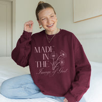 Woman wearing a maroon sweatshirt with text and floral design, sitting on a bed.
