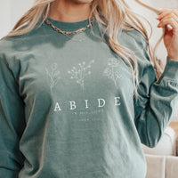 Person wearing a green sweatshirt with floral designs and text