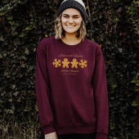 Person wearing a maroon sweatshirt with a Christmas design against a leafy background