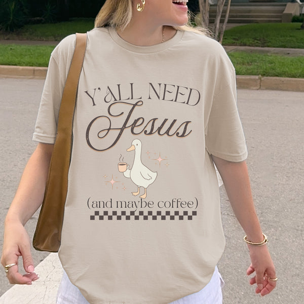 Person wearing a t-shirt with 'Y'all Need Jesus (and maybe coffee)' text and a goose graphic.
