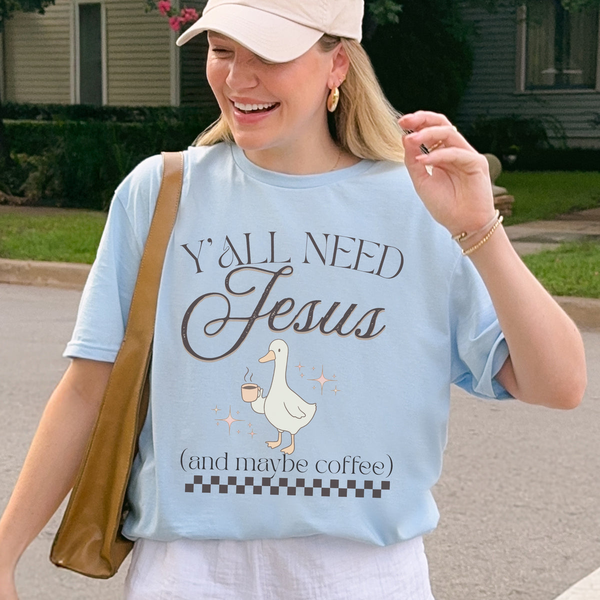 Person wearing a light blue t-shirt with a graphic and text, standing outdoors.