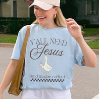 Person wearing a light blue t-shirt with a graphic and text, standing outdoors.