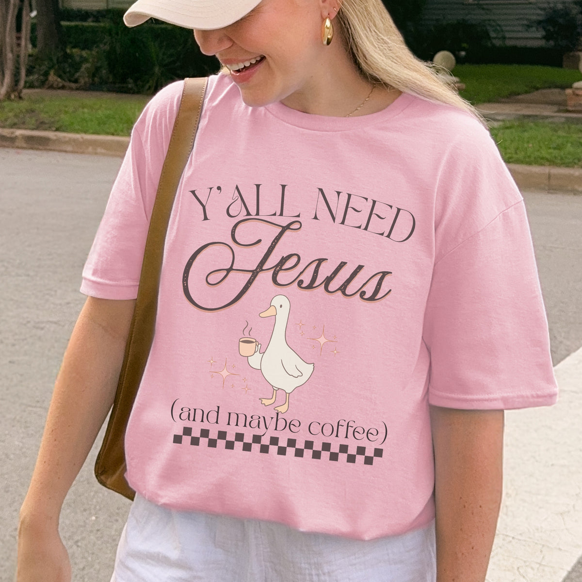 Person wearing a pink t-shirt with 'Y'all Need Jesus (and maybe coffee)' text and a goose graphic.