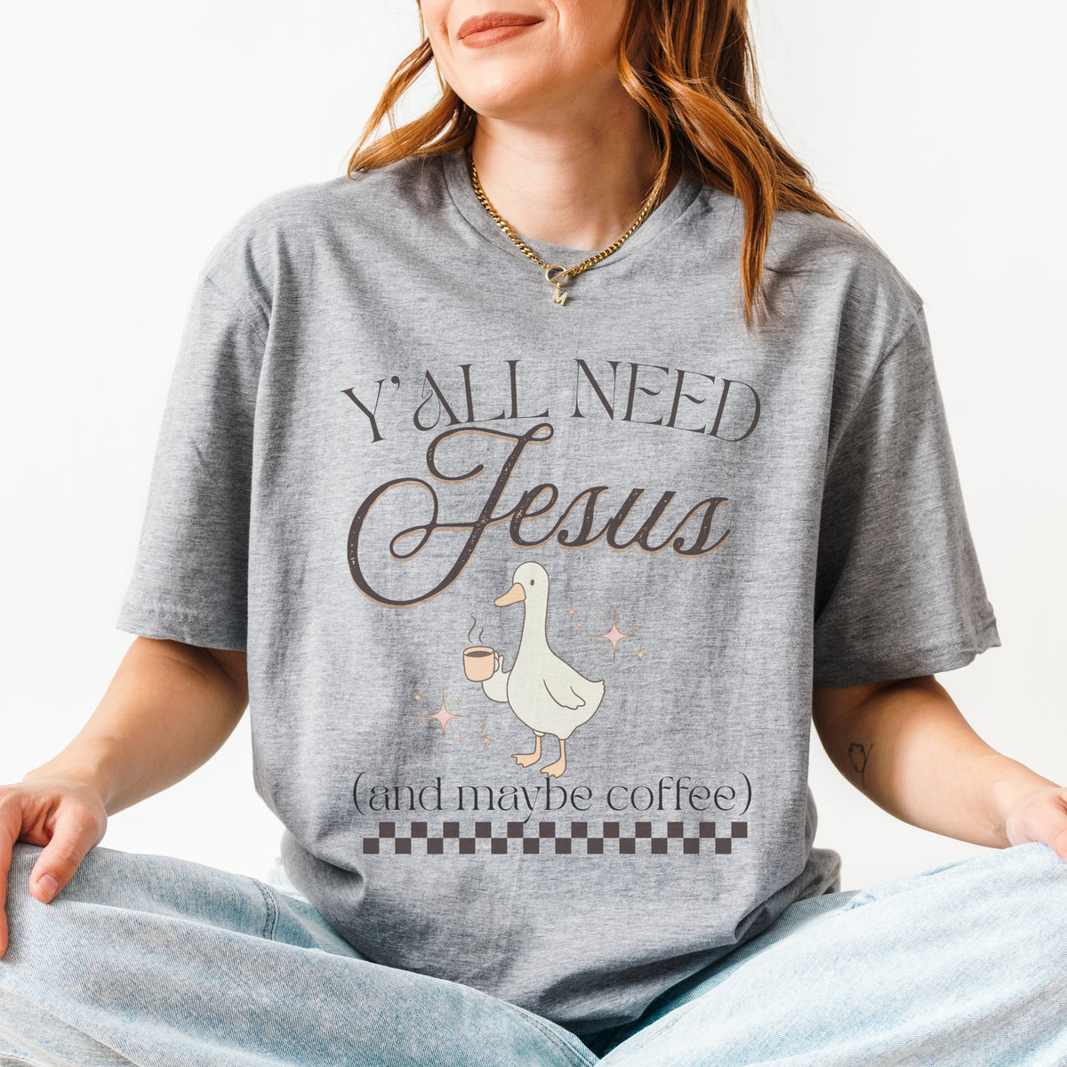 Person wearing a gray t-shirt with a graphic and text, sitting on a white background