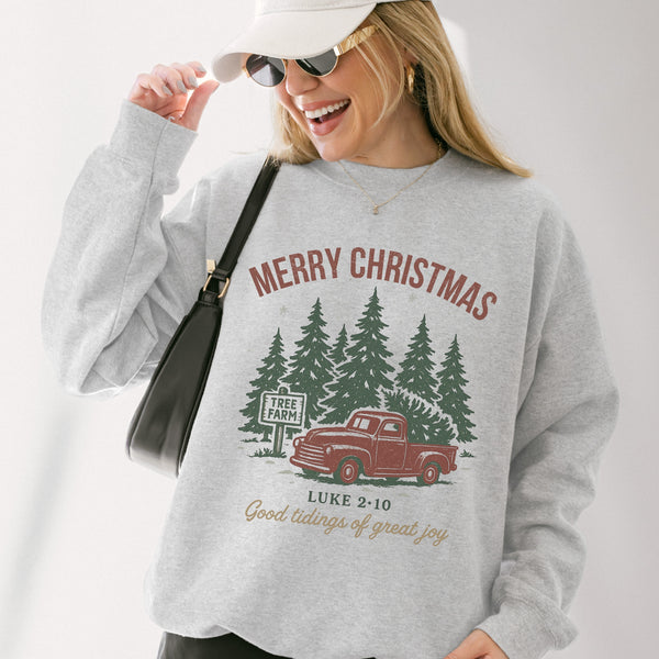 Person wearing a gray sweatshirt with a Christmas design featuring a truck and trees.