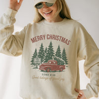 Person wearing a beige sweatshirt with a Christmas design featuring a red truck and trees.