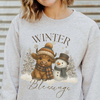 Gray sweatshirt with a winter-themed design featuring a cow and snowman, text 'Winter Blessings'.