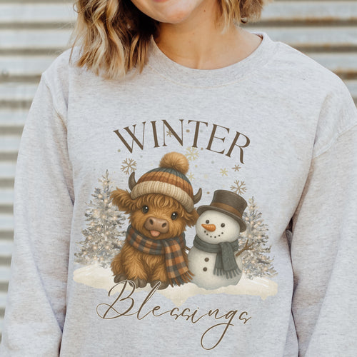 Gray sweatshirt with a winter-themed design featuring a cow and snowman, text 'Winter Blessings'.