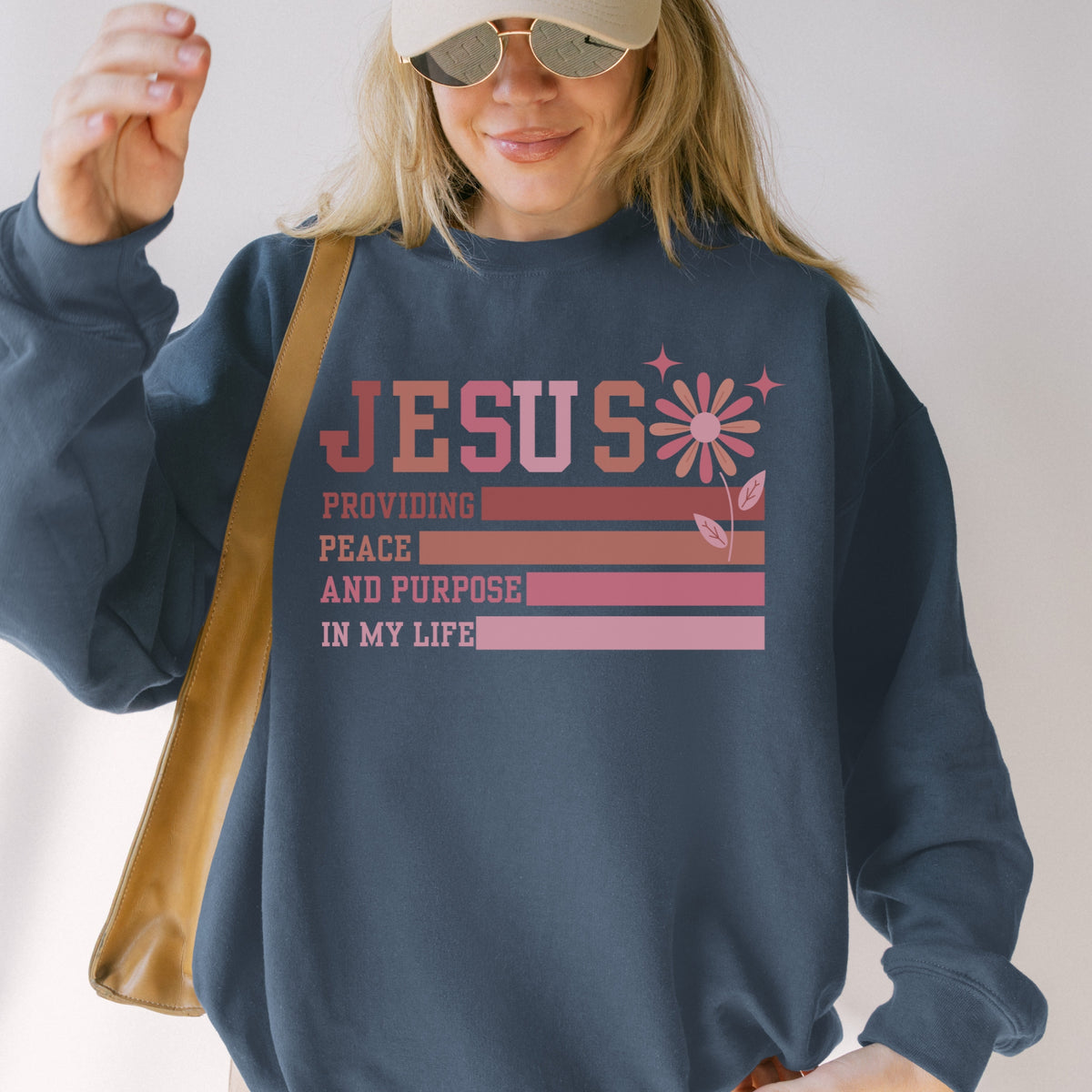 Person wearing a navy sweatshirt with 'Jesus providing peace and purpose in my life' text.