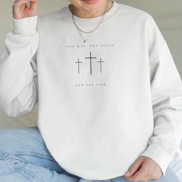 Person wearing a white sweatshirt with cross designs and text.
