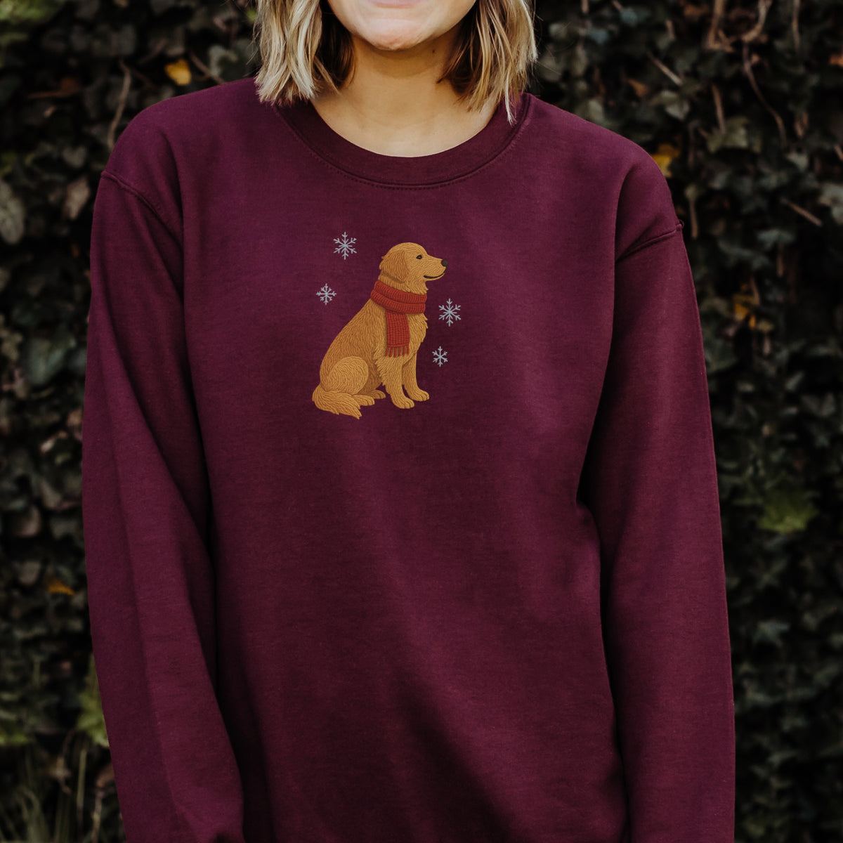 Person wearing a maroon sweatshirt with a dog design against a natural background