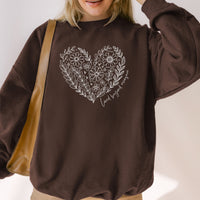 Person wearing a brown sweatshirt with a floral heart design on a plain background