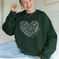 Person wearing a green sweatshirt with a floral heart design and text.