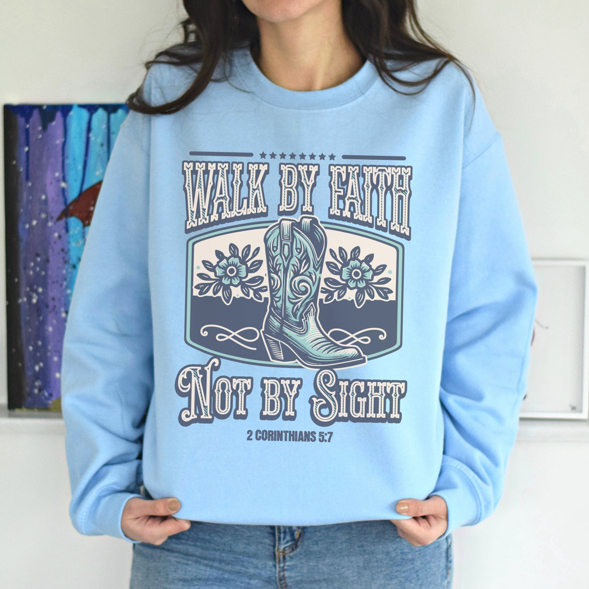 Light blue sweatshirt with cowboy boots and text design worn by a person.