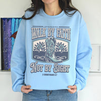 Light blue sweatshirt with cowboy boots and text design worn by a person.