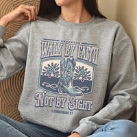 Person wearing a gray sweatshirt with a cowboy boot design and text.