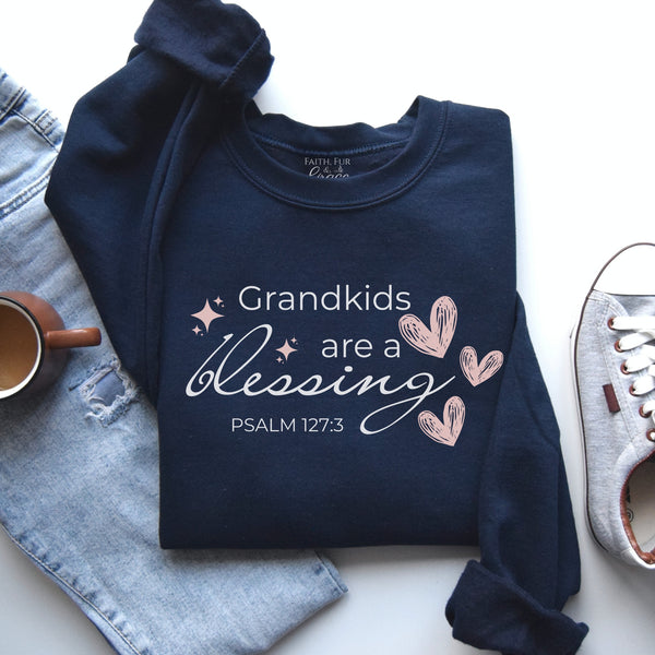 Navy blue sweatshirt with 'Grandkids are a blessing' text on a white surface with denim jeans and a mug.