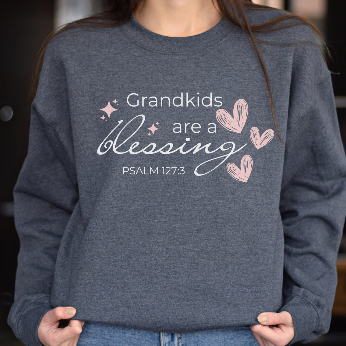 Person wearing a gray sweatshirt with 'Grandkids are a blessing' text and hearts design.