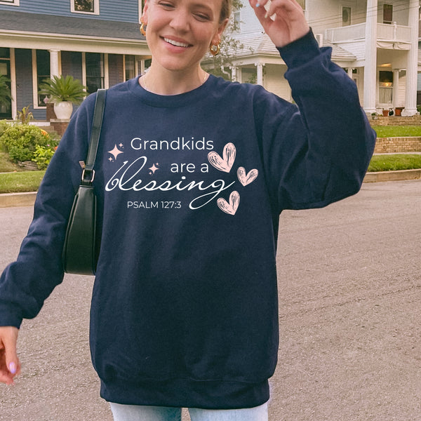 Person wearing a navy blue sweatshirt with text and hearts, standing in front of a house.