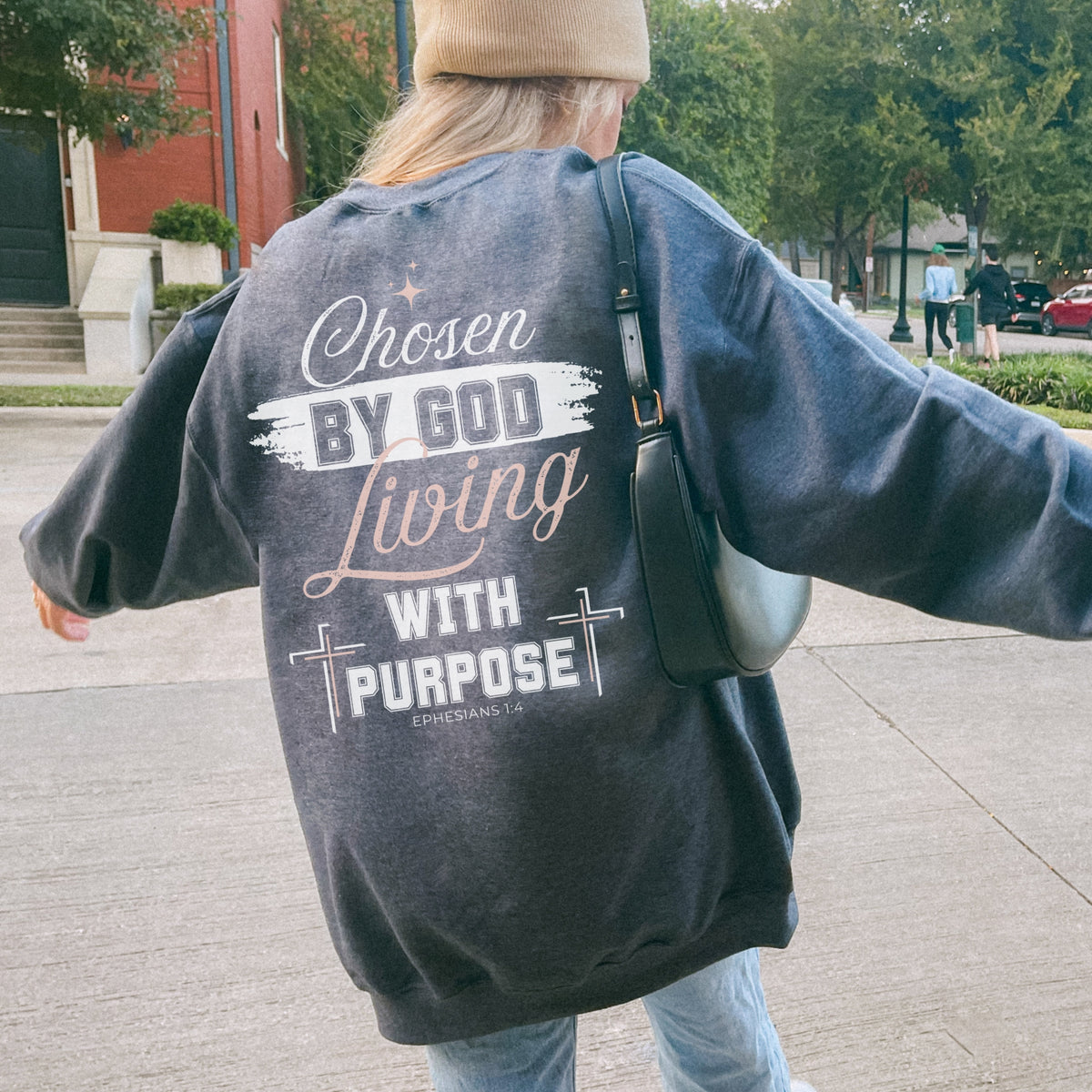 Person wearing a sweatshirt with a motivational message on the back, walking outdoors.
