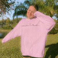 Person wearing a pink sweatshirt with 'freedom in Christ' text outdoors.