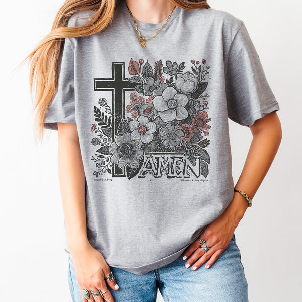 Person wearing a gray t-shirt with floral and cross design