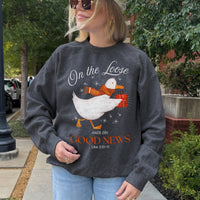 Person wearing a dark gray sweatshirt with a graphic and text, standing outdoors.