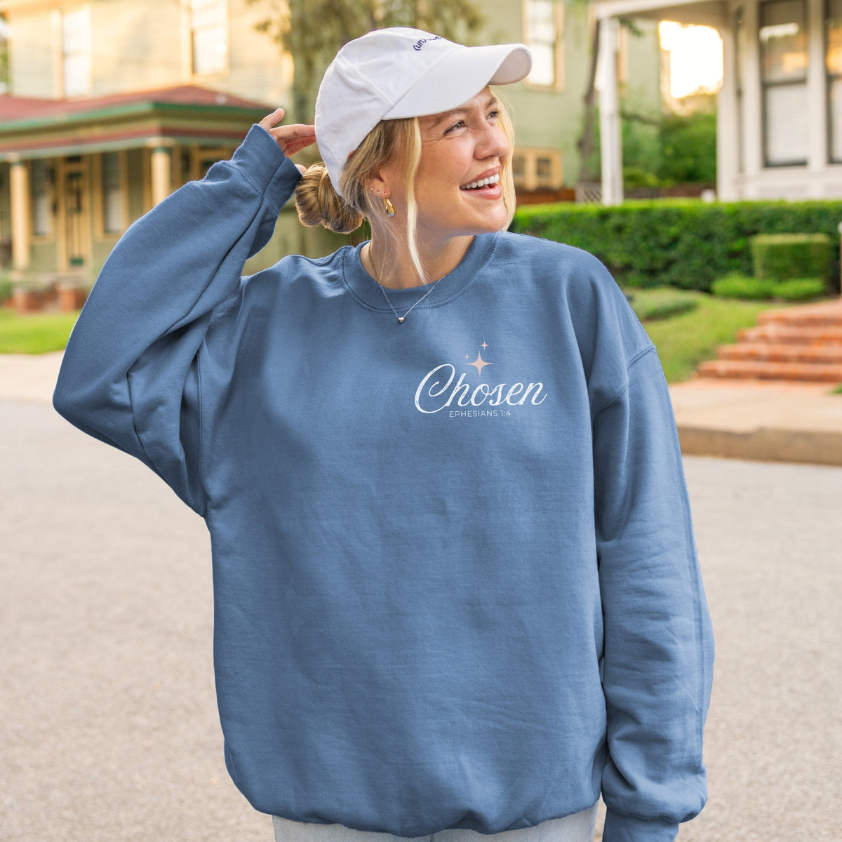 Person wearing a blue sweatshirt with 'Chosen' text outdoors.