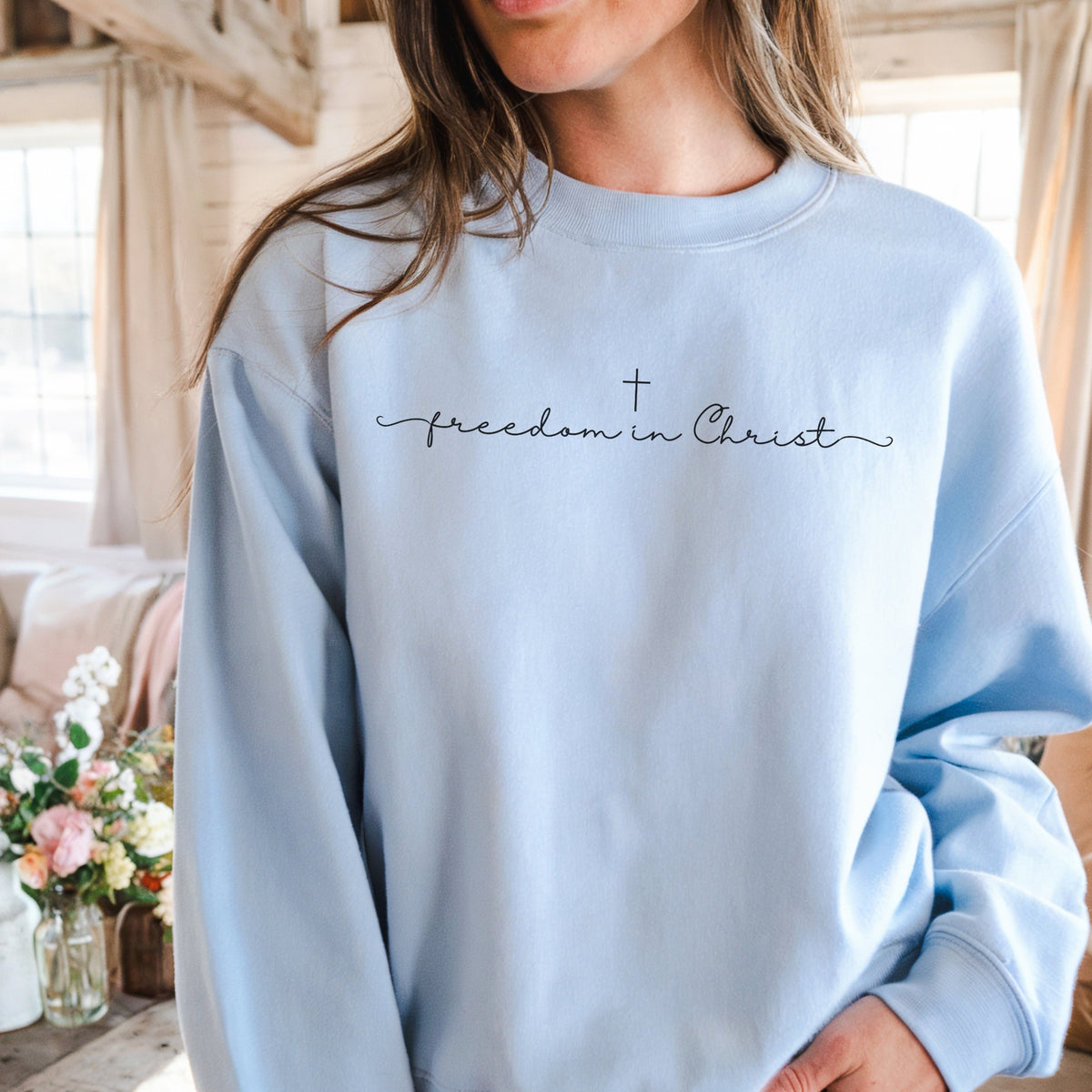 Light blue sweatshirt with 'freedom in Christ' text worn by a person indoors.