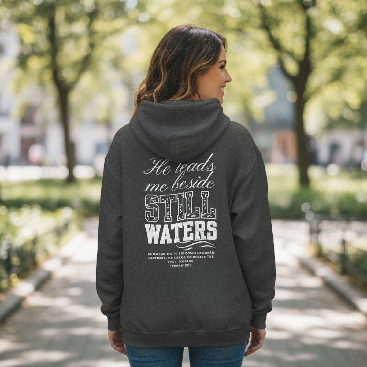 Person wearing a dark gray hoodie with text on the back, standing outdoors.