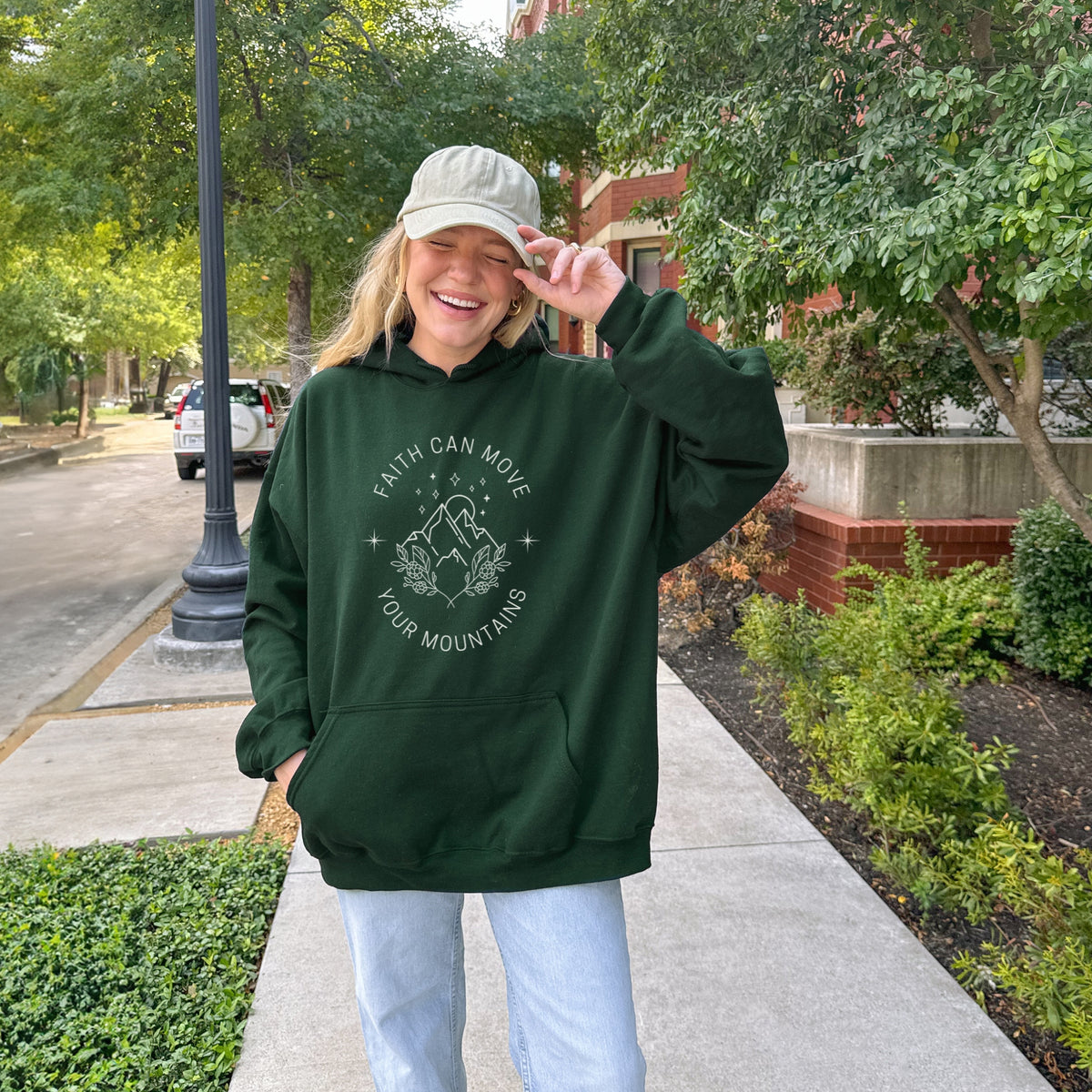 Person wearing a green hoodie with a motivational quote outdoors on a sidewalk.