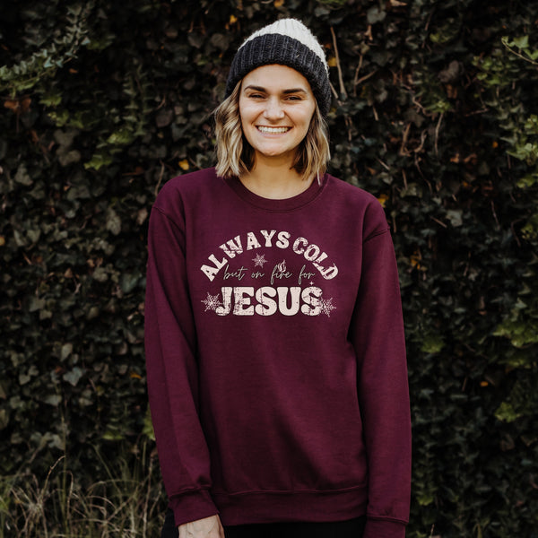 Person wearing a maroon sweatshirt with text standing against a leafy background