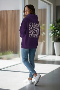 Woman wearing a purple hoodie with floral design in a modern indoor setting